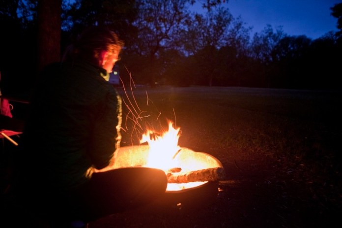 woman stoking fire at dusk, brazos bend state park, texas