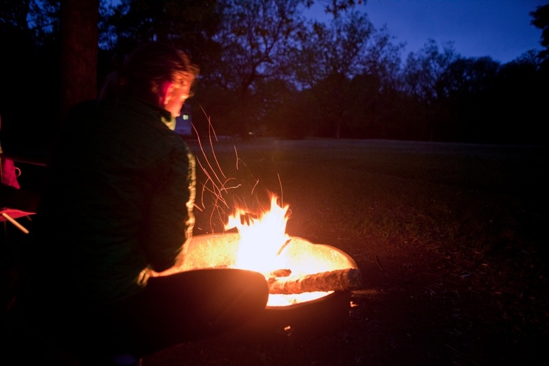 woman stoking fire at dusk, brazos bend state park, texas