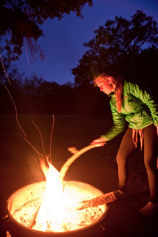 woman stoking fire at dusk, brazos bend state park, texas