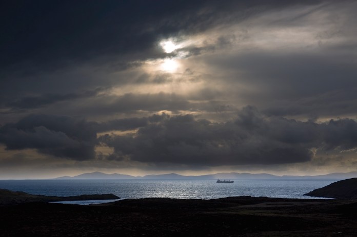 A ship passes through the dramatic light of Duntulm Bay
