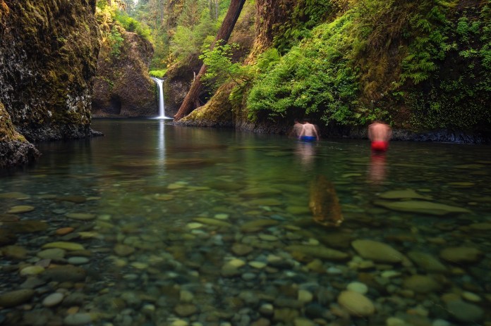 Two men wade to get a closer look at Punchbowl Falls