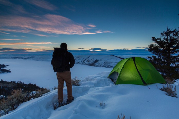 Man hiking up to a winter campsite overlooking Fremont Lake in Bridger National Forest, Wy