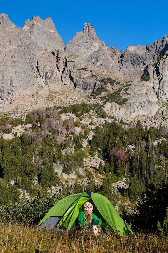 A woman emerging from her tent with her dog at the Cirque of the Towers in the southern Winds